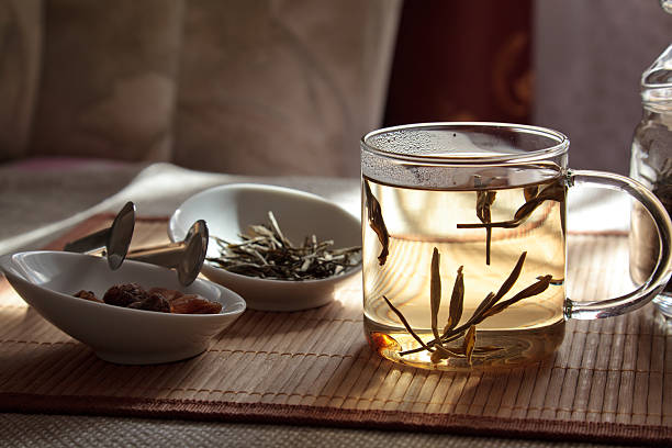 Glass cup, filled with boiled herbal tea and two bowls with brown sugar and dry petals on table with tablecloth.\n\n[url=http://www.istockphoto.com/search/lightbox/11815046]ALL HD FOOTAGE AND PHOTO LIGHTBOX from the same session and on same theme[/url]