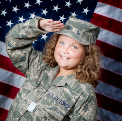 Ten year old little girl in military uniform saluting