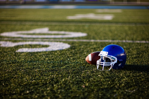 An American football helmet and football on the football field. Perfect image for your football announcement.