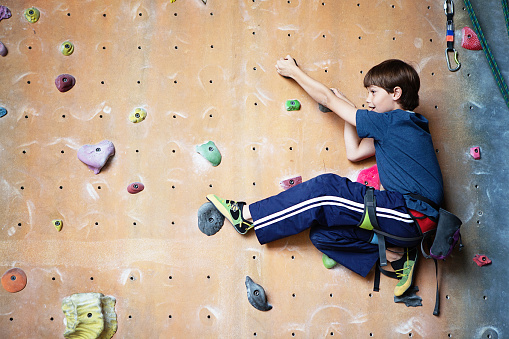 10 year old boy climbing on a rock climbing wall