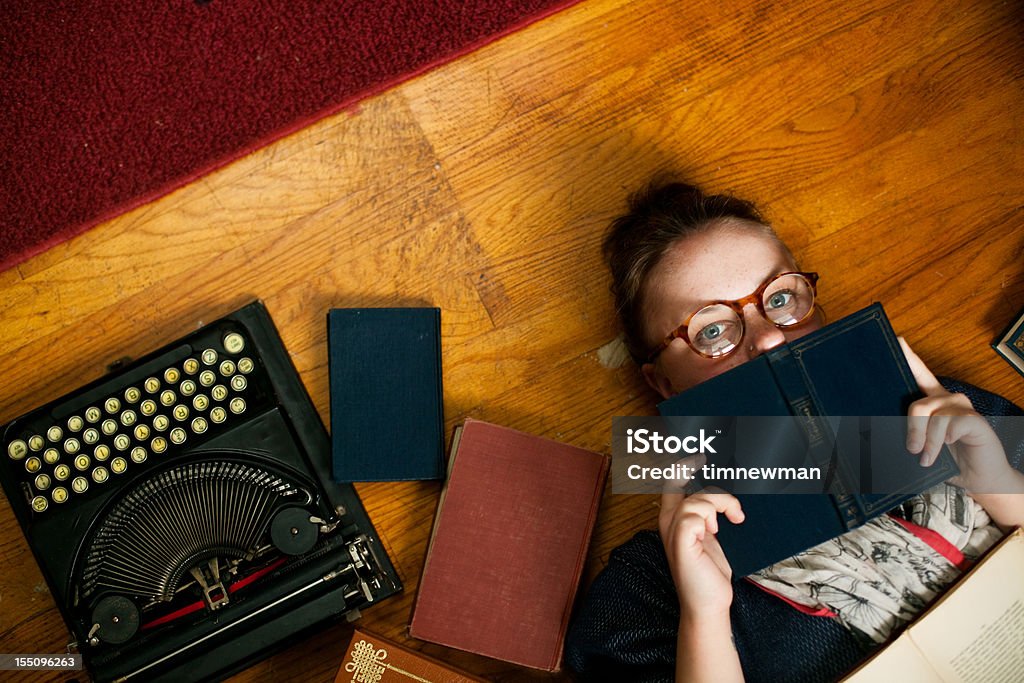 Étudiant de la jeune fille sur le sol, des livres et une machine à écrire - Photo de Raconter une histoire libre de droits