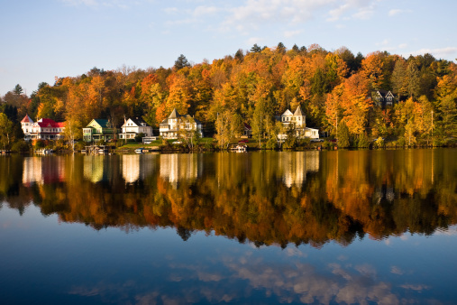 A mirror like reflection of Saranac Lake shoreline in the Adirondack park in New York