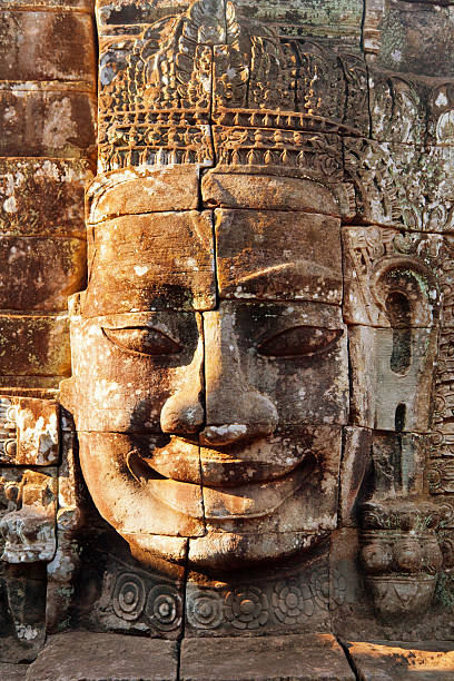 Dramatic view at sunset of one of the many large stone carved faces of Bayon Temple in Angkor Thom, Angkor district, Siem Reap, Cambodia