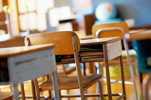 classroom with empty wooden desks - education stockfoto's en -beelden