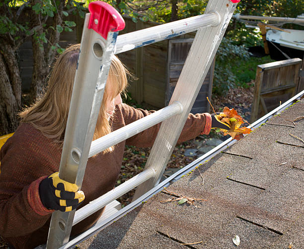Autumn Gutter or Eavestrough Cleaning Senior Woman. stock photo