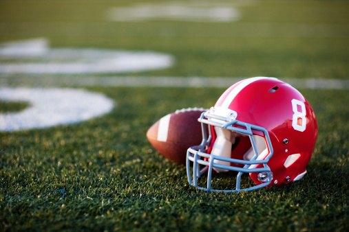 A red American football helmet and football on the football field. Perfect image for your football announcement.