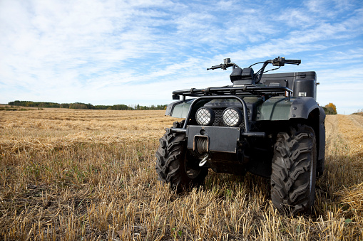 An all terrain vehicle (quad) in a farmers' harvested field.