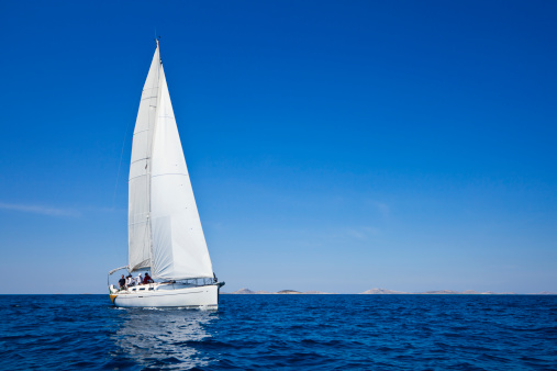 The view through the spray of how the two sailboats are heeling at sunset, boat roll, splashes shine in the sun, sailors on the boards. High quality photo