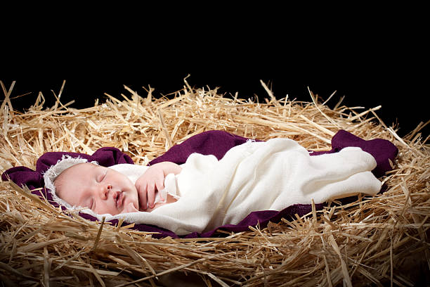 Nativity with Baby Sleeping in Manger Nativity scene with a newborn baby boy wrapped in a woven blanket on top of a purple blanket, sleeping in a manger. bed of hay stock pictures, royalty-free photos & images