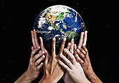 Hands cradling Mother Earth against starfield background