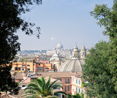 A scenic view over Rome, framed by trees, taken near the top of the Spanish Steps.