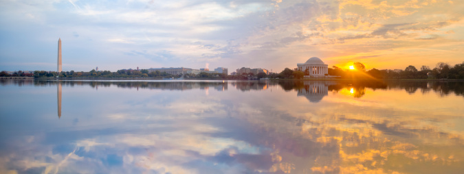 Panoramic image of the Tidal Basin at sunrise with the Washington Monument and the Jefferson Memorial.