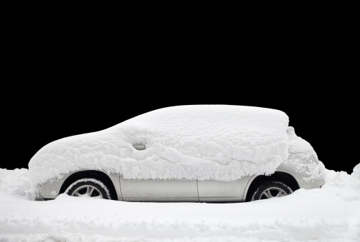 a parked car covered in deep snow against black