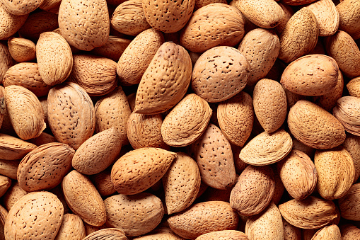 Background of big raw unpeeled almonds situated arbitrarily. Top view.