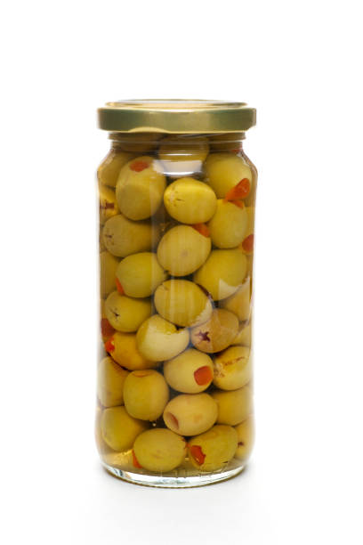 Close up traditional artisanal pickled green olives and natural wooden scoop in a rustic barrel on retail display of open market, high angle view