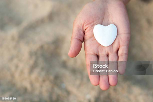 Foto de Abra Mão Segurando Um Coração Em Defocused Fundo De Areia e mais fotos de stock de Passar