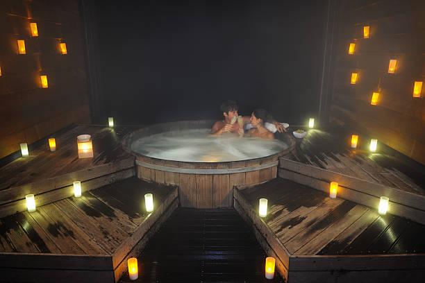 casal brindando em uma banheira de hidromassagem - couple hot tub spa treatment health spa - fotografias e filmes do acervo