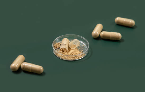 istock Taking dietary supplements with capsules. One capsule Opened in a jar on green 1550985088
