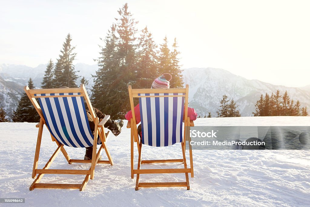 Winter Sun therapy heliotherapy People sitting outdoors on a sunny winter day,, at the top of a mountain at a helitheraphy place on German alps. Chair Stock Photo
