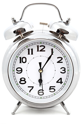 Five alarm clocks of different colors show different times. Start of the day, waking up, morning, different time zones.