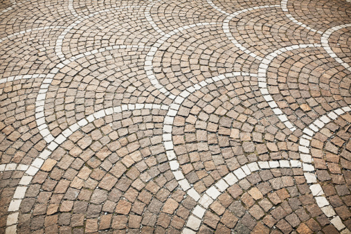 An outdoor stone floor surface arranged in fan-shaped curved patterns.