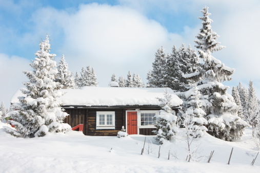 Cozy secluded snowbound log wooden cabin with smoking chimney among snow covered fir tree forest high in alpine mountains at winter day. With no people 3D illustration from my 3D rendering.