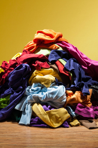 Huge pile heap of dirty clothes on golden background. Houseworks: stack of messy, colorful men's and women's clothes ready for laundry or ironing on golden background.