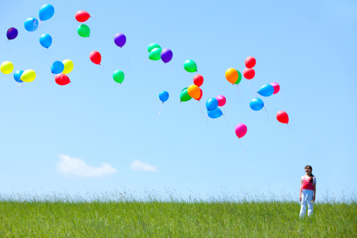 Girl flying helium balloons outdoors. Adobe RGB