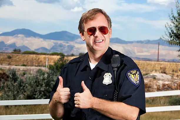 friendly policeman with a beautiful background and thumbs up
