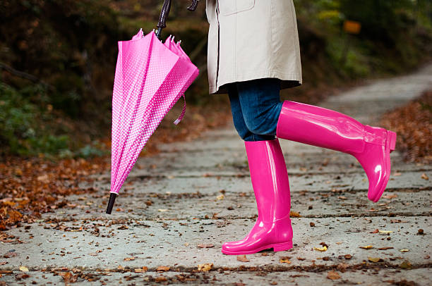 Woman with umbrella wearing rubber boots  rubber boot stock pictures, royalty-free photos & images