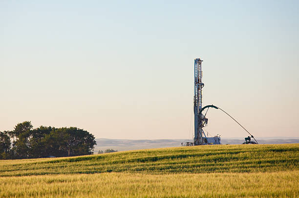 Drilling Rig on the Prairie A drilling rig on the plains. Alberta, Canada. Horizontal colour image. Alberta's economy is very much derived from oil and gas industry. Crude oil is a major export and economic driver of the western province. This image was taken near Drumheller in a region that is known for its abundance of gas and oil deposits. Themes include drilling, fracking, oil, gas, industry, rig, platform, boom, hydrolic, agriculture, great plains, and Canada. Nobody is in the image, taken early on a summer morning.  oil pump oil industry alberta equipment stock pictures, royalty-free photos & images