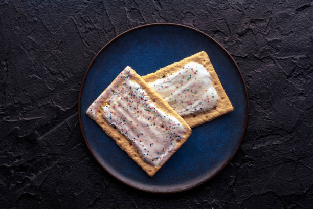 istock Pop tarts on a plate. Poptart toaster pastry with icing on black 1551011109