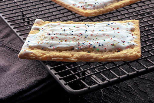 Pop tart on a baking rack. A poptart toaster pastry with icing on a black background