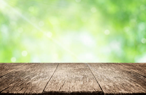istock Empty wooden table over green background. Summer background with space for product display 1551023375