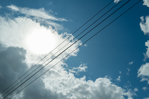 Abstract view of high telephone and fibre optic cables seen against a summer sky.  A storm is developing.