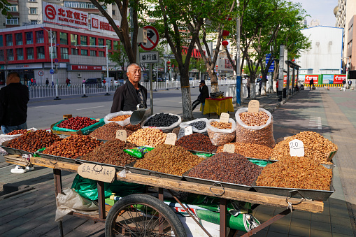 Urumqi, Xinjiang - October 13, 2016: One of the most visually rewarding destinations in Xinjiang’s capital is the Urumqi International Bazaar (also known as the “Grand Bazaar”). Nestled in the heart of Uyghur, Hui and Russian neighborhoods, it claims to be the largest bazaar in the world. A lot tourists are in the Bazaar. Different snack, dry fruit, and food are selling at the Bazzar.