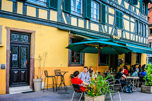 People sitting outside the old timber-framed restaurant Ar' miseau in Strasbourg, France