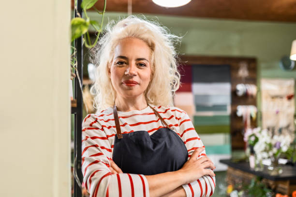 istock Flower shop worker looking at camera leaning on wall 1551111927