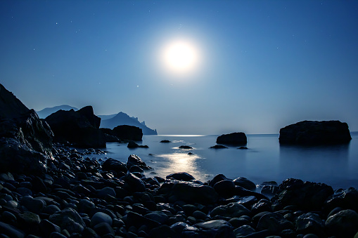 The full moon shines space on the stone seashore. landscape in nature