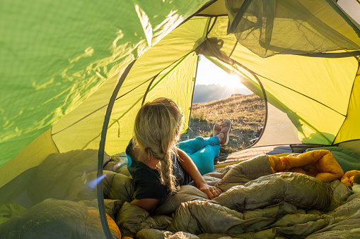 She sets up the tent at sunset, high up in the mountains,
