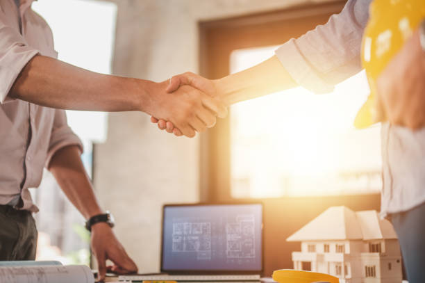 istock engineers shake hands for meet up and brainstorm to prepare blueprint architecture project builder. 1551171616
