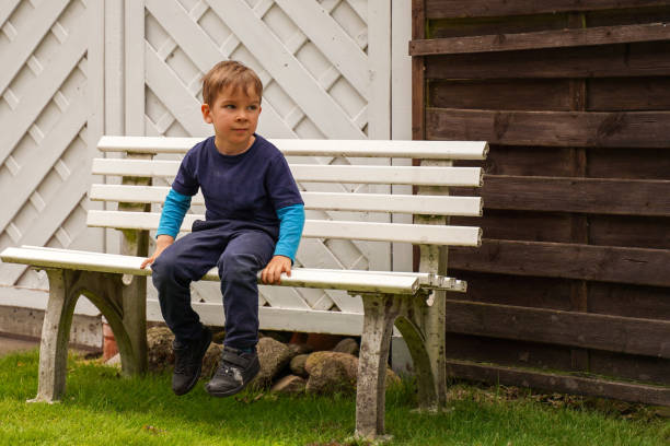 Rural child sitting alone on a bench in the park