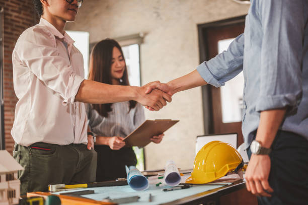 istock engineer and foreman shake hands for meet and brainstorm to prepare blueprint architecture project. 1551178101