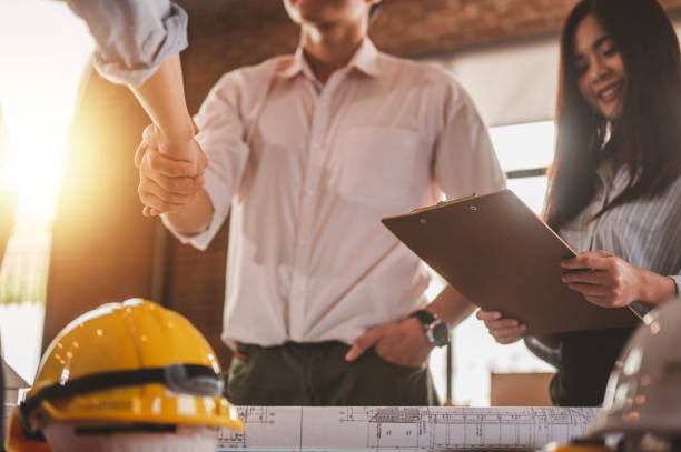 istock engineer and foreman shake hands for meet and brainstorm to prepare blueprint architecture project. 1551178104
