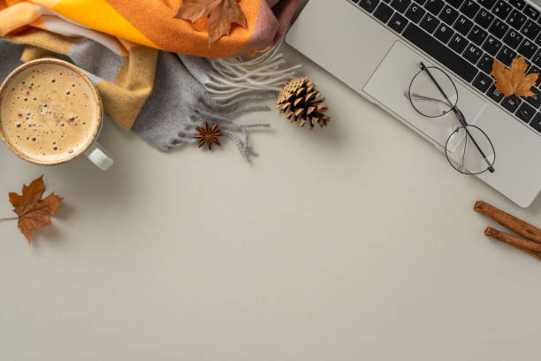 istock A top view image encapsulates the essence of working from home, showcasing a laptop with a cozy blanket, pinecones, spices, glasses and a cup of coffee on grey isolated backdrop, offers copyspace 1551179161