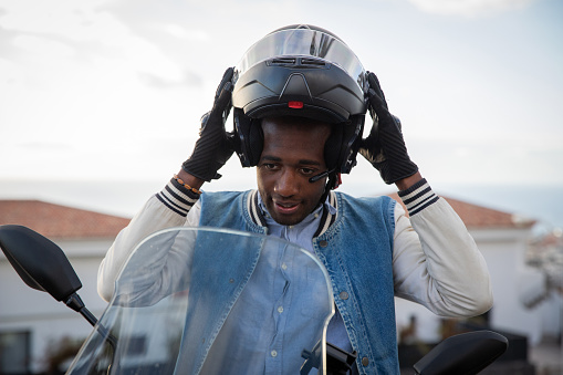A motorcyclist puts on his helmet before driving his motorcycle, road safety concept