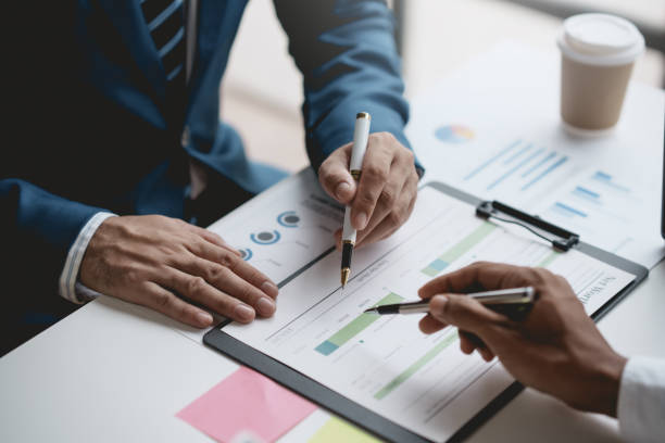 istock Group of business people working together on new project with planning analytical report at meeting. Businesspeople meeting together pointing to graph assess business profits. 1551209303