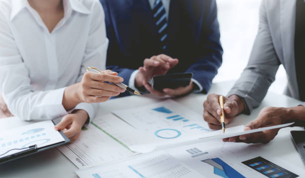 Group of business people working together on new project with planning analytical report at meeting. Businesspeople meeting together pointing to graph assess business profits.