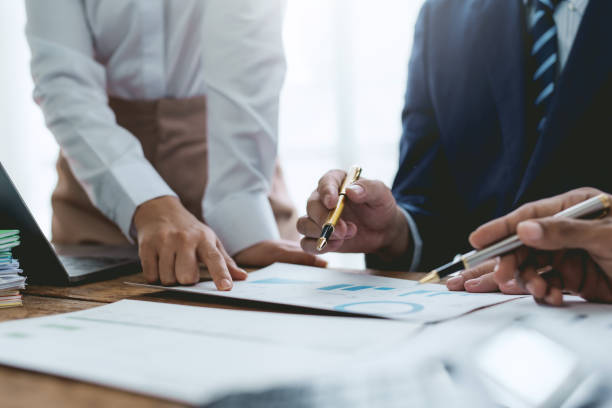 istock Group of business people working together on new project with planning analytical report at meeting. Businesspeople meeting together pointing to graph assess business profits. 1551209307