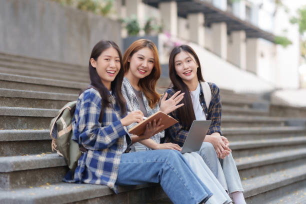 istock Group Of Young Asian Students Collaborating Outdoors at University. Teamwork and Knowledge Sharing. Asian Students Engaged in Collaborative Learning Outdoors. 1551209612